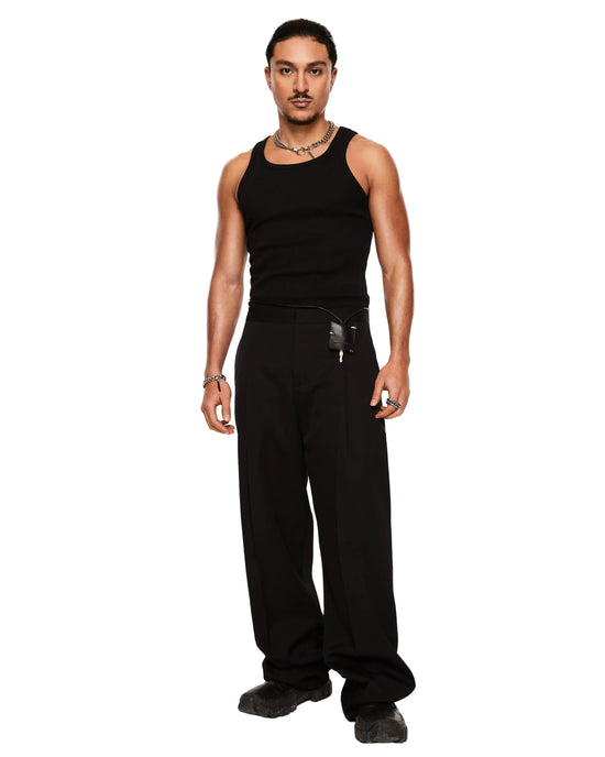 A man modeling a black ribbed tank top and black wide-leg trousers against a plain white studio background.