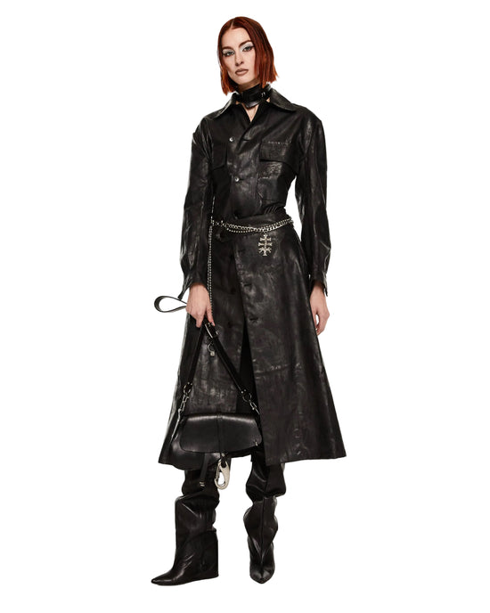 Person wearing a long black leather coat and boots on a white background