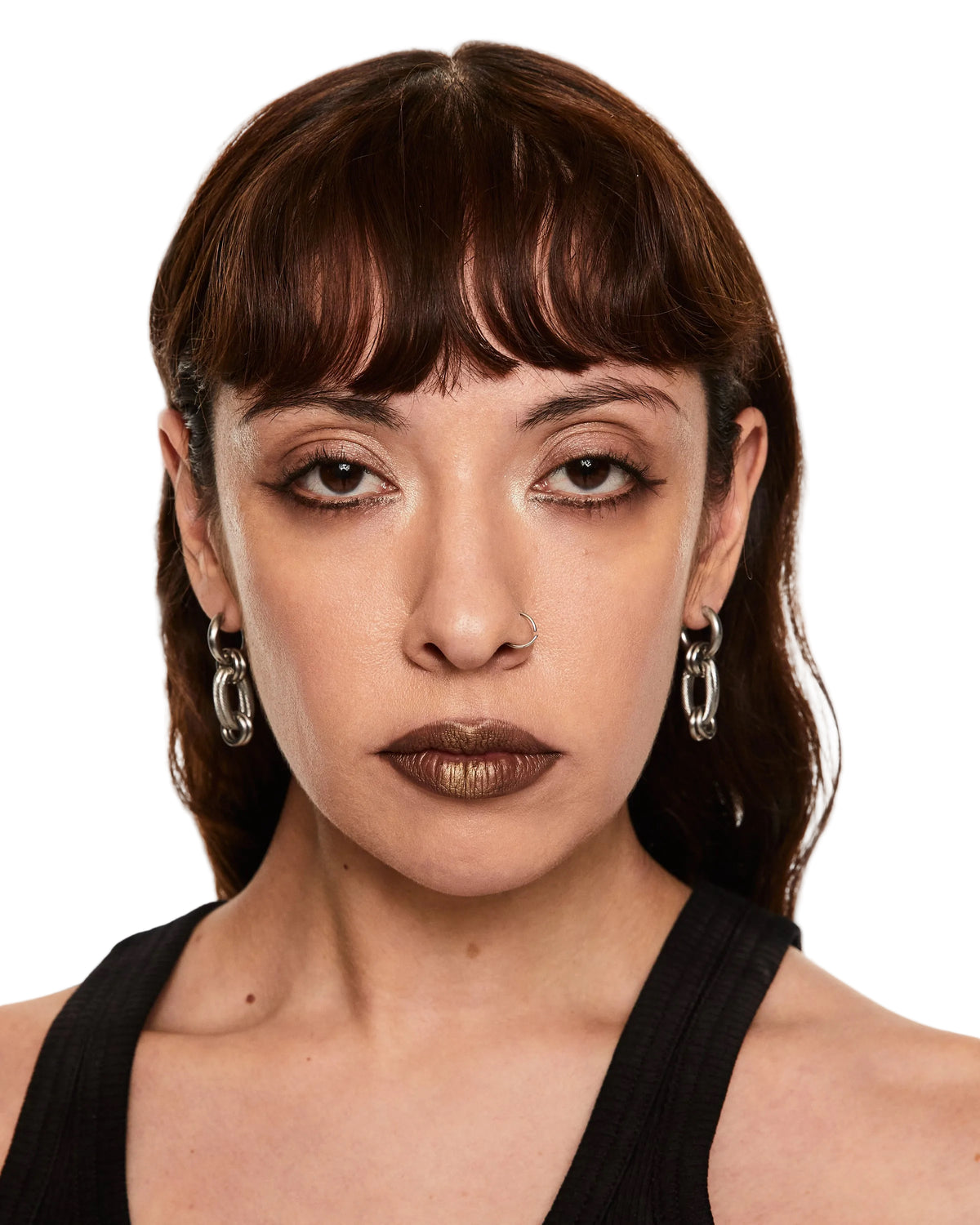 Woman with dark hair and earrings against a white background