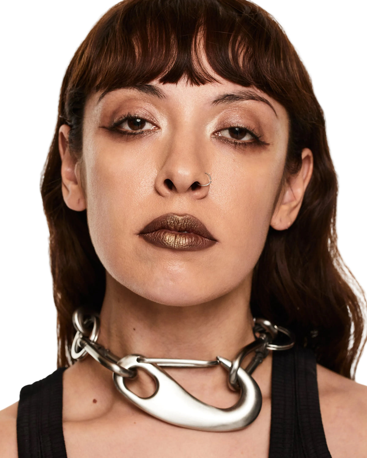 Woman wearing a large silver necklace against a neutral background